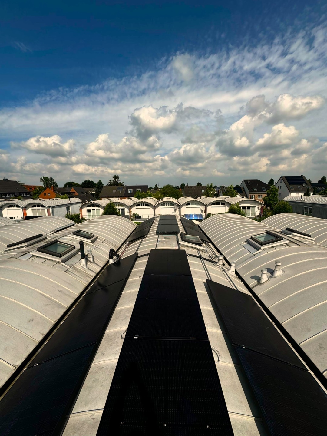 Photovoltaik-Module auf den Tonnendächern der Cybele AV Studios unter blauem Himmel